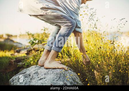Niedriger Abschnitt des jungen Mannes, der auf Felsen durch Blumen steht Stockfoto