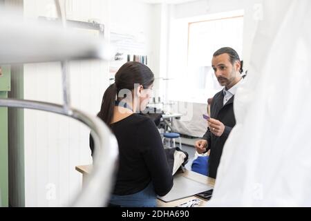 Reife männliche Kunden und weibliche Unternehmer reden an der Kasse in Waschsalon Stockfoto