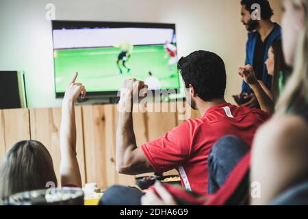 Männliche und weibliche Freunde sehen Fußballspiel im Fernsehen an Zu Hause Stockfoto