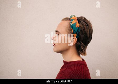 Seitenansicht eines jungen Mannes, der gegen eine weiße Wand steht Stockfoto