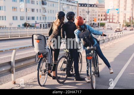 Rückansicht des Mannes, der Selfie mit weiblichen Freunden nimmt Fahrräder auf der Straße Stockfoto