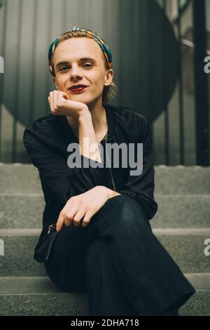 Porträt eines lächelnden jungen Mannes, der auf der Treppe sitzt Stockfoto