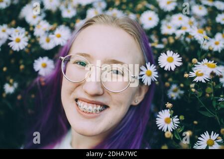 Portrait von lächelnd Teenager-Mädchen mit Zahnspangen inmitten Gänseblümchen Blüte Anlagen Stockfoto