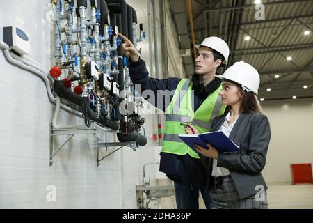 Weibliche Projektmanagerin im Business-Anzug und weiß hart hat hält ein Notizbuch und bespricht mit dem Chief die Produktdetails Ingenieur in einem neuen Flugzeug ma Stockfoto