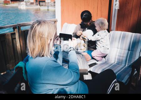 Freund fotografieren Frau spielen mit Kindern über Smartphone an Ferienvilla Stockfoto