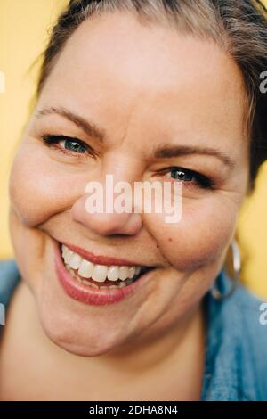 Nahaufnahme Porträt von lächelnden reifen Frau vor gelbem Hintergrund Stockfoto