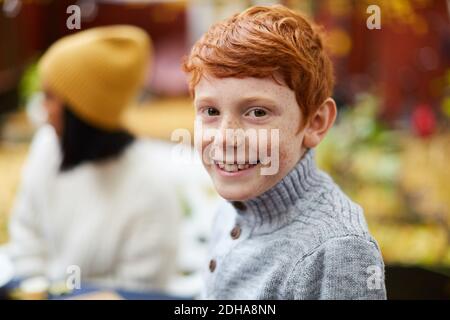 Porträt eines lächelnden Jungen, der auf dem Hof sitzt Stockfoto