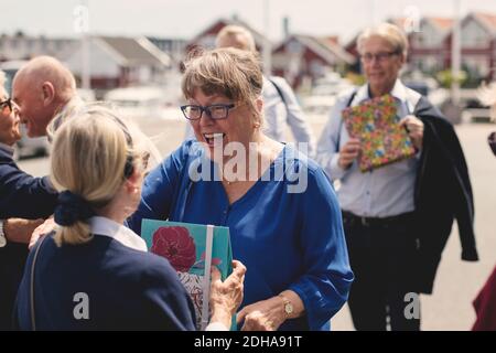 Glückliche ältere männliche und weibliche Freunde begrüßen mit Geschenken im Freien Stockfoto
