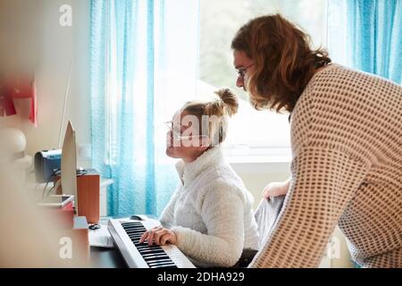 Hausmeister mit behinderter Frau, die zu Hause Klavier spielt Stockfoto