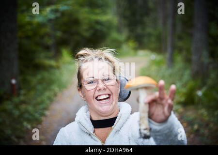 Porträt einer behinderten jungen Frau, die Pilze im Wald hält Stockfoto