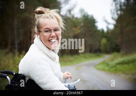 Porträt einer lächelnden jungen behinderten Frau, die im Rollstuhl sitzt Straße Stockfoto