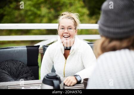 Lächelnde behinderte Frau, die auf den männlichen Hausmeister schaut, der am Tisch sitzt Im Hinterhof Stockfoto