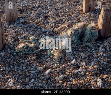 Ausrangierte Seile und Teile von Fischernetzen auf dem Kies-und Kiesstrand gesehen. Stockfoto