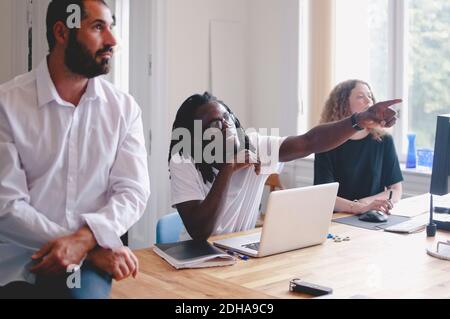 Junger Geschäftsmann zeigt etwas, um Kollegen während der Sitzung in kreativ Büro Stockfoto