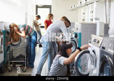 Universitätsstudenten, die Waschmaschinen im Campus-Waschsalon benutzen Stockfoto