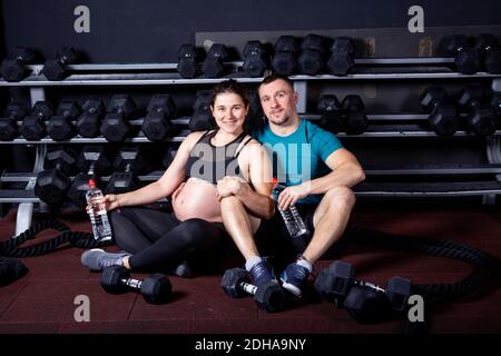 Sport Familie Schwangerschaft in städtischen Cross-Training Turnhalle. Sport und gesunder Lebensstil während der Schwangerschaft. Junges Paar umarmt auf Turnhalle fl Stockfoto