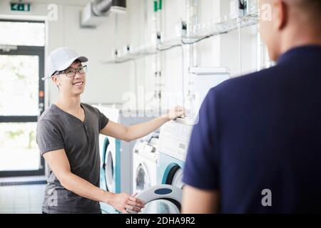 Lächelnder Mann, der mit einem Universitätsfreund während der Wäsche spricht Stockfoto