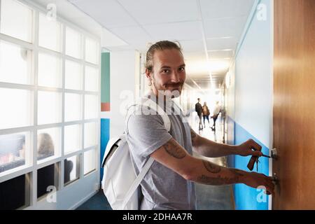 Porträt eines Mannes, der die Tür öffnet, während die Schüler im Flur stehen An der Universität Stockfoto