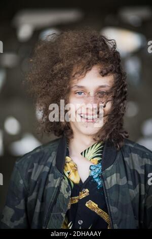 Portrait von lächelndem Teenager mit lockigen braunen Haaren an Parkhaus Stockfoto