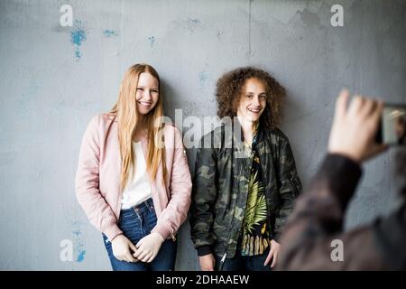 Zugeschnittenes Bild von Teenager-Mädchen fotografieren Freunde stehen gegen Wand In der Parkgarage Stockfoto