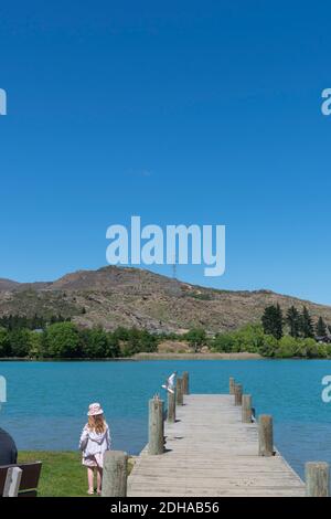 Cromwell New Zealand - November 10 2020; Mädchen steht und schaut Möwe fliegen vorbei Pier in der Stadt historischen Bezirk. Stockfoto