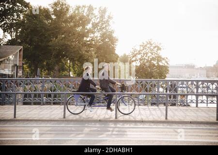 Volle Länge Seitenansicht des älteren Paares genießen Tandem Fahrrad Fahren Sie auf der Brücke Stockfoto