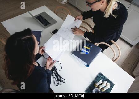 High-Angle-Ansicht der weiblichen Ingenieure diskutieren über Blaupause bei Tisch im Home Office Stockfoto