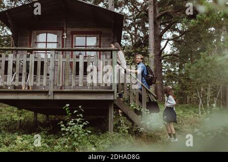 Familie mit Gepäck zu Fuß über die Treppe des Hauses im Wald Während der Ferien Stockfoto