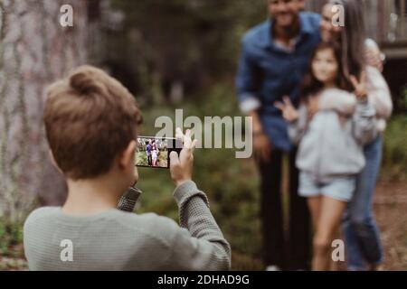 Junge fotografieren Familie mit Handy im Stehen Im Hinterhof Stockfoto