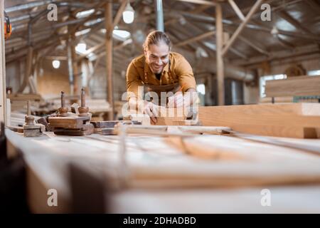 Schöner Zimmermann, der mit dem Holz arbeitet, die Bar mit dem Flugzeug in der Schreinerei hobeln Stockfoto