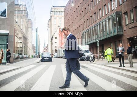 Reifer Geschäftsmann mit Telefon beim Gehen auf Zebra Kreuzung in Stadt Stockfoto