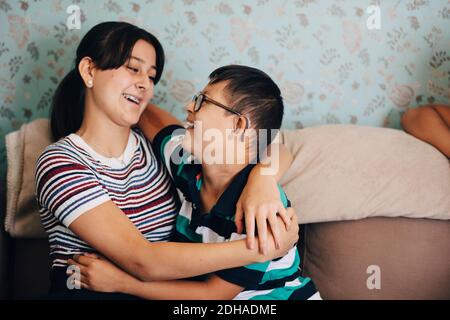 Liebevoller Bruder und Schwester umarmen sich auf dem Sofa gegen die Wand Wohnzimmer Stockfoto