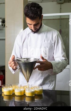 Konditor arbeitet Dosieren der Desserts in Glas. Stockfoto