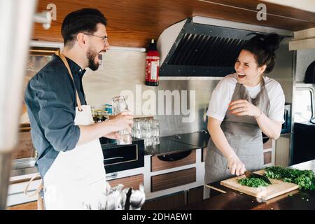 Männliche und weibliche Unternehmer lachen, während sie im Food Truck stehen Stockfoto