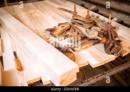 Vintage-Planken und Planken auf der Werkbank in der Zimmerei Kaufen Stockfoto