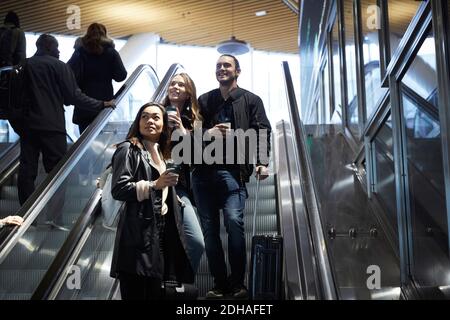 Blick aus der unteren Perspektive auf Freunde mit Gepäck, das auf der Rolltreppe steht An der U-Bahn-Station Stockfoto