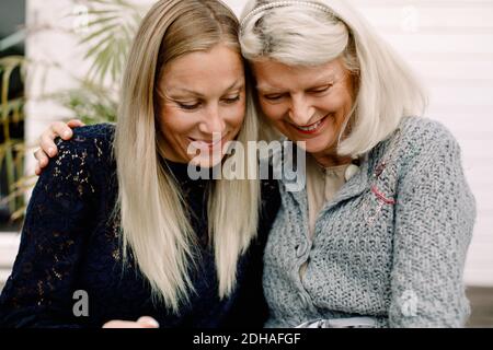 Lächelnde Mutter und Tochter mit Arm um die Wand herum Stockfoto