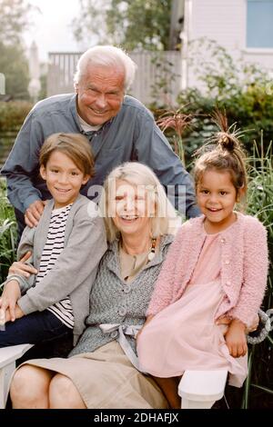 Porträt von Großeltern und Enkelkindern im Hinterhof sitzen Stockfoto