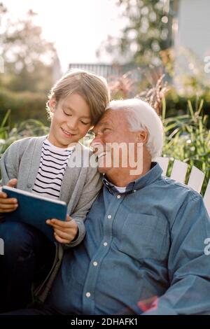 Lächelnder Großvater und Enkel mit digitalen Tablet im Hinterhof Stockfoto