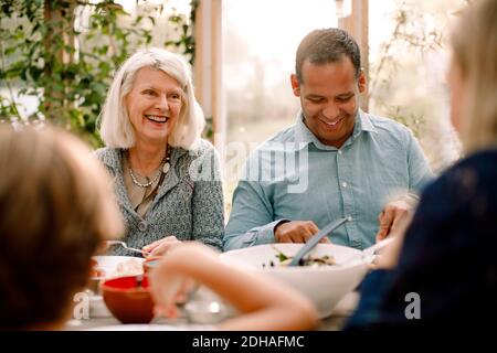 Lächelnde Familie, die während des Essens am Esstisch sitzt Mittagessen Stockfoto