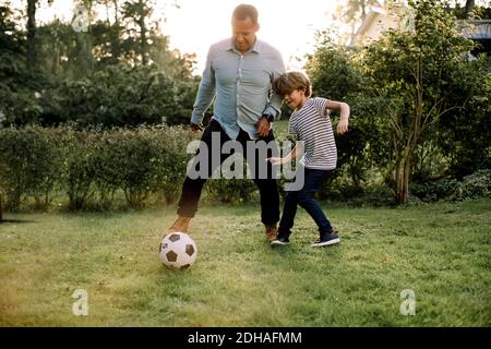 Voller Länge von Vater und Sohn Fußball spielen im Hinterhof Am Wochenende Aktivitäten Stockfoto