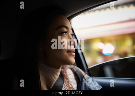 Nachdenkliche junge Frau, die durch das Fenster schaut, während sie im Auto sitzt Stockfoto