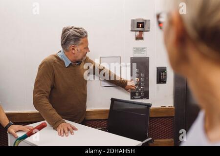 Reifer Geschäftsmann drückt die Aufzugstaste beim Umzug in ein neues Büro Stockfoto