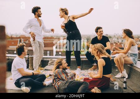 Fröhliche Menschen tanzen, während sie Musik mit Freunden auf der Terrasse genießen Auf der Dachparty Stockfoto