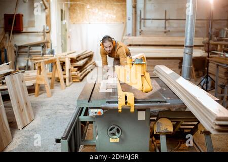 Zimmermannsarbeit Sägen Holzbohlen mit Kreissäge in der Schreinerei-Lager Stockfoto