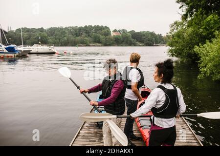 Ältere Frauen und Mann mit Kajaks und Paddeln auf dem Steg Während des Kajakkurses Stockfoto