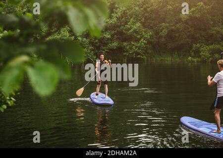 Ältere Frau und Mann lernen während des SUP Paddelboarding im Meer Kurs Stockfoto