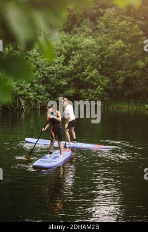 Ältere Männer und Frauen lernen während der SUP Paddeltouren im Meer Kurs Stockfoto