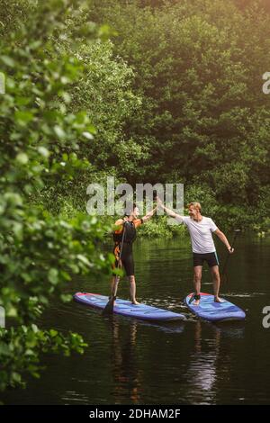 Ältere Frau und Mann hoch fiving beim Lernen Paddleboarding im Meer Während des SUP-Kurses Stockfoto