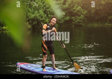 Porträt einer lächelnden älteren Frau, die während des SUP im Meer paddelt Kurs Stockfoto